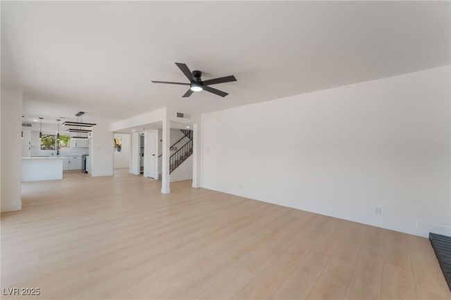 Unfurnished living room with a ceiling fan, light wood-type flooring, and stairway | Image 9