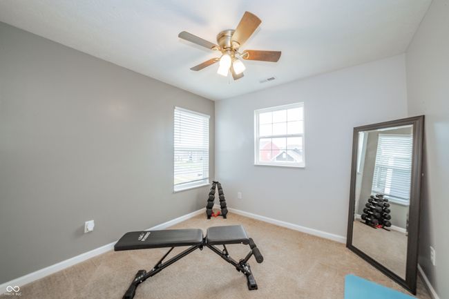 exercise room with baseboards, a ceiling fan, and light colored carpet | Image 25