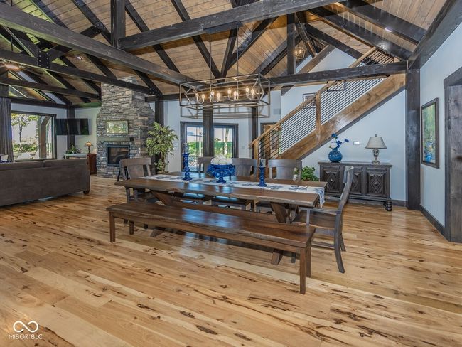 dining area featuring a chandelier, light wood-style flooring, a stone fireplace, healthy amount of natural light, and high vaulted ceiling | Image 13