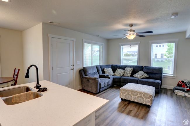 Living area featuring wood finished floors, a textured ceiling, visible vents, ceiling fan, and baseboards | Image 8