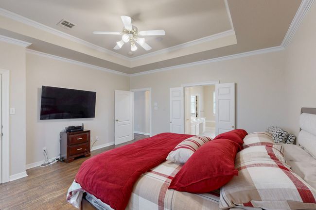 Bedroom with wood finished floors, visible vents, ornamental molding, ensuite bath, and baseboards | Image 18