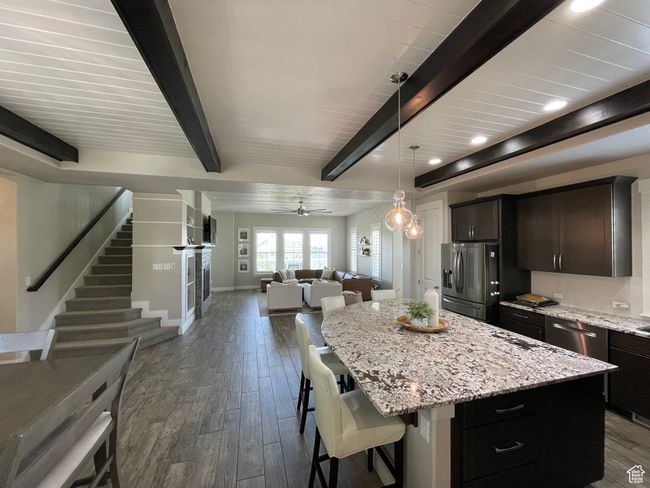 Kitchen with stainless steel appliances, oversized island, wood-style tile, and beamed ceiling. | Image 15