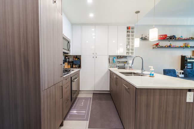 Kitchen with modern cabinets, a sink, oven, a peninsula, and white cabinets | Image 4