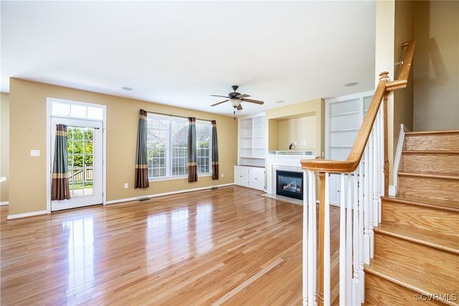 Unfurnished living room featuring healthy amount of natural light, light wood-style flooring, a fireplace with flush hearth, and a ceiling fan | Image 14