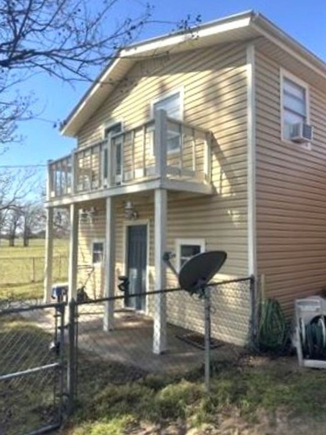 View of home's exterior featuring a balcony, cooling unit, fence, and a gate | Image 4