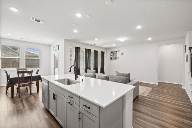 Kitchen with recessed lighting, wood finished floors, visible vents, stainless steel dishwasher, and a sink | Image 10