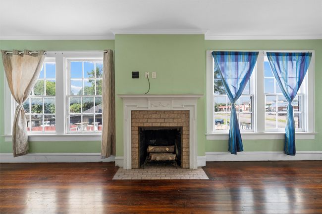 Unfurnished living room featuring wood-type flooring, crown molding, and a brick fireplace | Image 25
