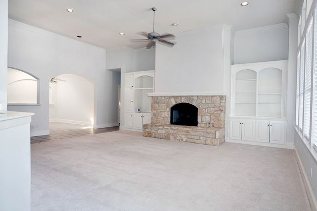 Unfurnished living room featuring a stone fireplace, a ceiling fan, crown molding, recessed lighting, and carpet flooring | Image 7