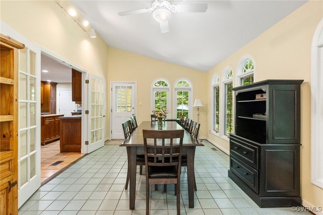 Dining room featuring french doors, light tile patterned flooring, rail lighting, lofted ceiling, and a ceiling fan | Image 17