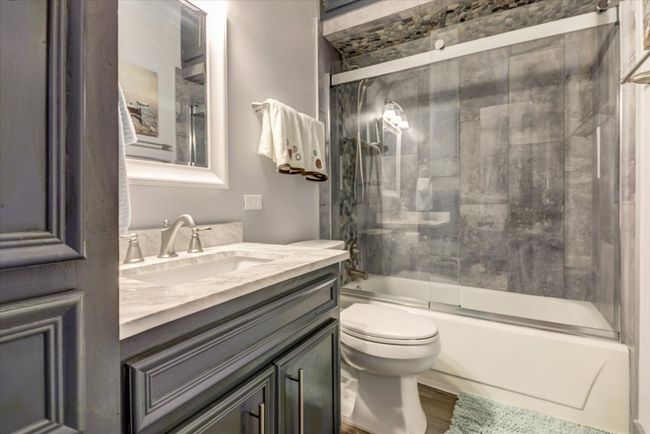 Bathroom featuring vanity, wood finished floors, and bath / shower combo with glass door | Image 16