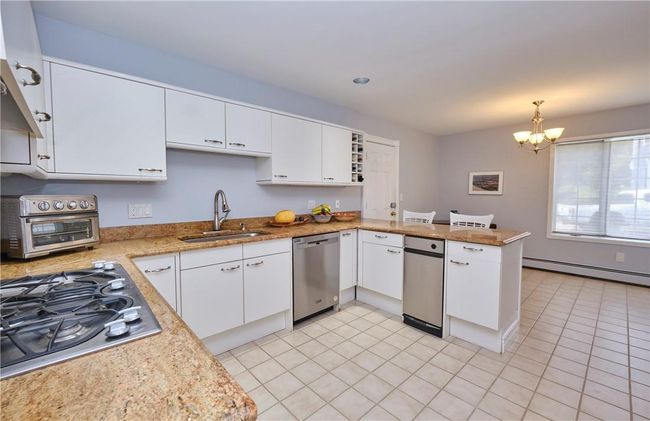 Kitchen featuring baseboard heating, a chandelier, sink, kitchen peninsula, and stainless steel appliances | Image 20