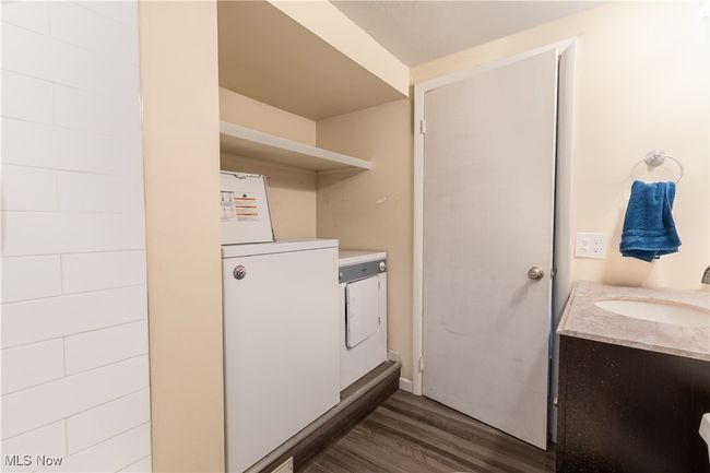 Washroom featuring laundry area, dark wood-style floors, a sink, and washer and clothes dryer | Image 12