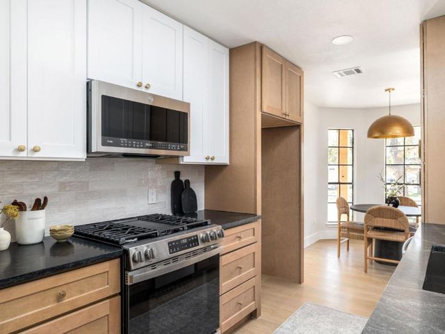 Kitchen with appliances with stainless steel finishes, light wood-style flooring, visible vents, white cabinets, and decorative backsplash | Image 15