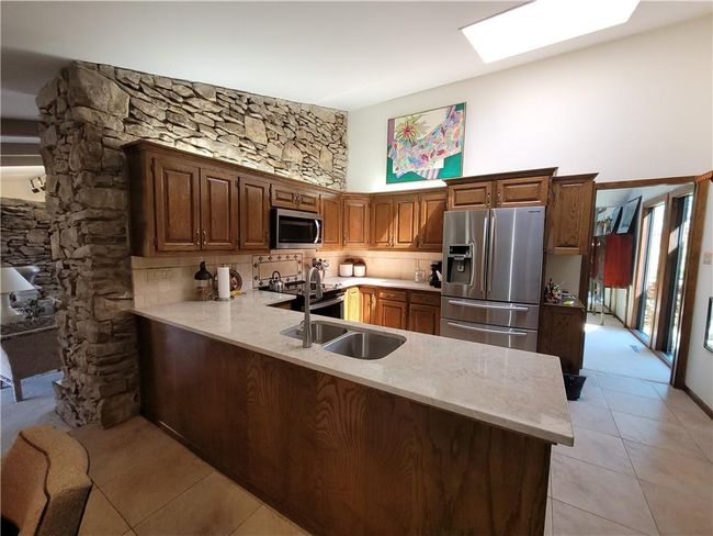 Kitchen featuring light tile patterned floors, stainless steel appliances, a peninsula, and tasteful backsplash | Image 22