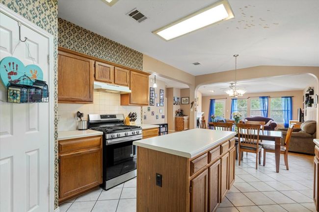 Kitchen with gas stove, under cabinet range hood, arched walkways, open floor plan, and lofted ceiling | Image 12