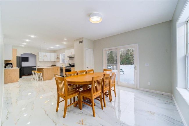 Dining area with light marble finish floors, baseboards, arched walkways, and recessed lighting. Access to rear deck. | Image 13