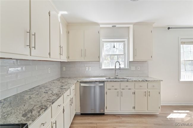 Kitchen featuring stainless steel dishwasher, light wood-style flooring, backsplash, light stone counters, and crown molding | Image 8