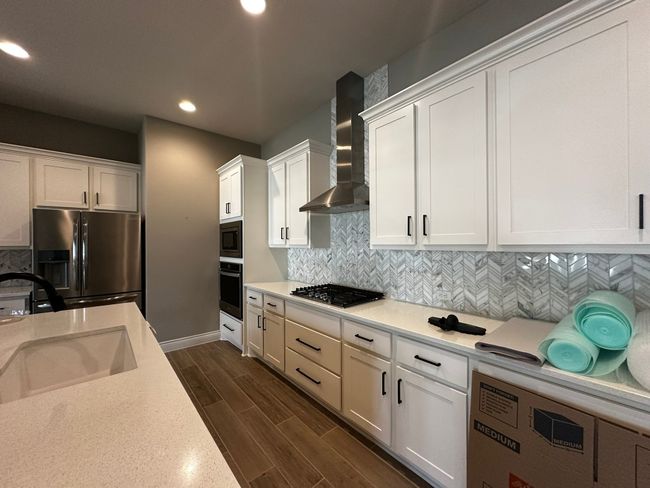 Kitchen with wall chimney range hood, appliances with stainless steel finishes, recessed lighting, white cabinets, and backsplash | Image 8