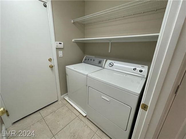 Washroom featuring light tile patterned floors, washing machine and clothes dryer, and laundry area | Image 15