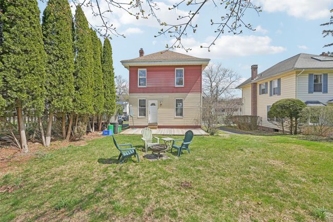 Back of house with a chimney, a fire pit, and a lawn | Image 37