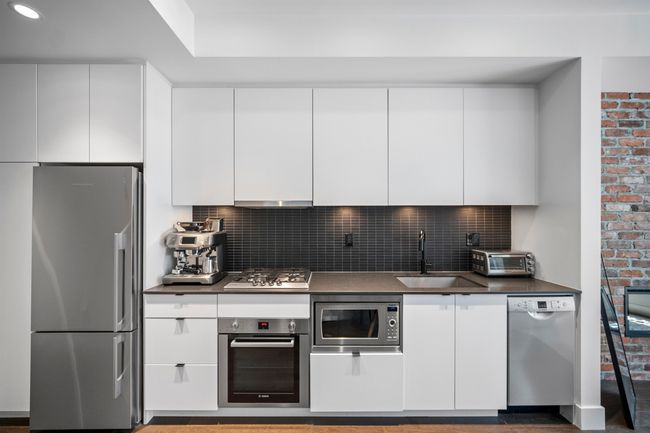 Kitchen featuring white cabinetry, stainless steel appliances, backsplash, and modern cabinets | Image 4