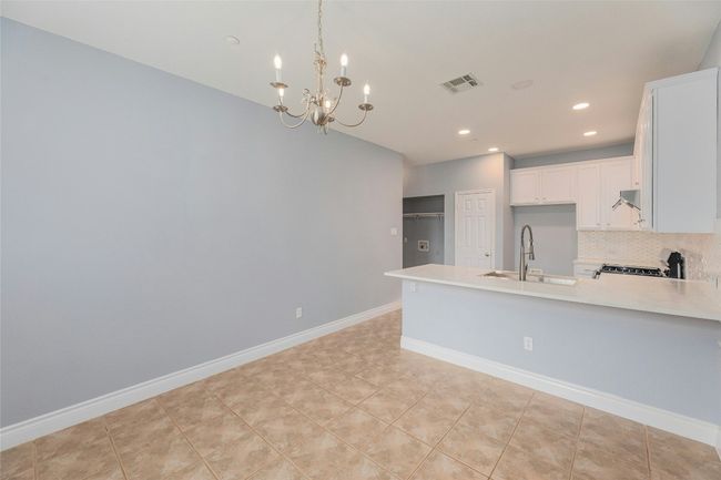 Kitchen with a peninsula, light countertops, white cabinetry, a chandelier, and tasteful backsplash | Image 10