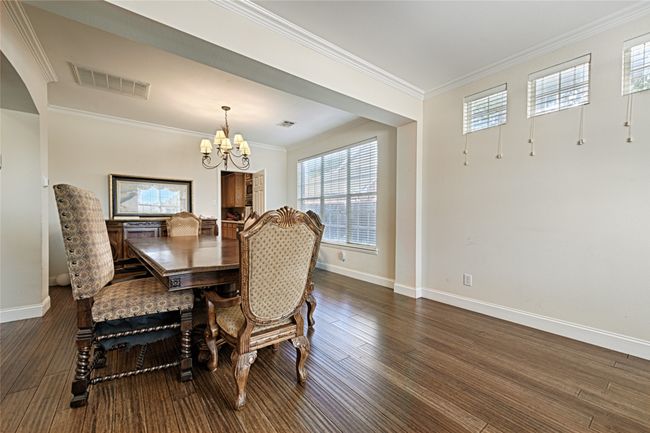 Dining area with baseboards, visible vents, ornamental molding, dark wood-type flooring, and a notable chandelier | Image 25