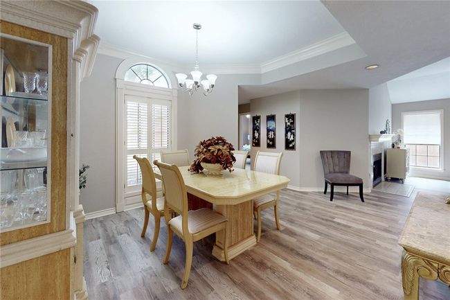 Dining area featuring light wood finished floors, healthy amount of natural light, a chandelier, crown molding, and baseboards | Image 4