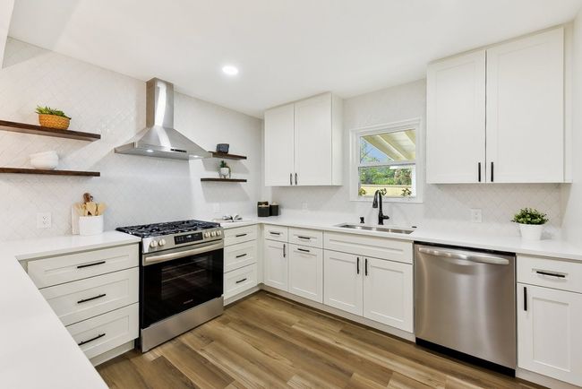 Kitchen with a sink, wall chimney range hood, wood finished floors, stainless steel appliances, and open shelves | Image 8