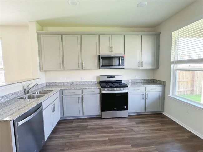 Kitchen with stainless steel appliances, a sink, healthy amount of natural light, and light stone counters | Image 6