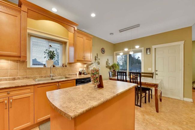 Kitchen featuring a sink, tasteful backsplash, light countertops, a kitchen island, and dishwasher | Image 24