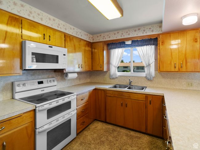 Kitchen featuring white appliances, a sink, light countertops, custom cabinets, and decorative backsplash | Image 9