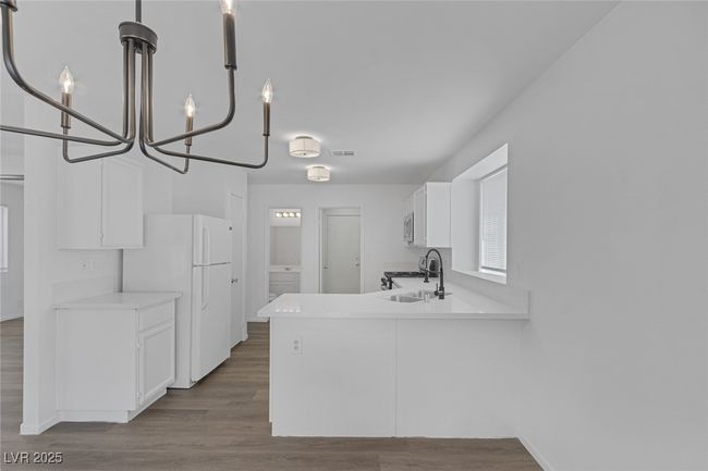 Kitchen featuring freestanding refrigerator, white cabinets, dark wood-type flooring, and light countertops | Image 9