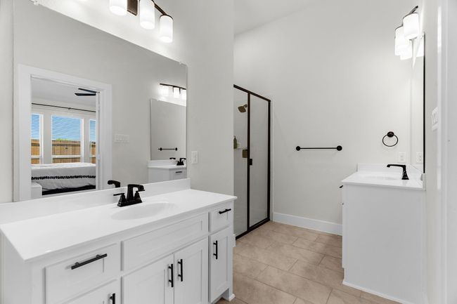 Ensuite bathroom featuring two vanities, a stall shower, tile patterned floors, and baseboards | Image 28