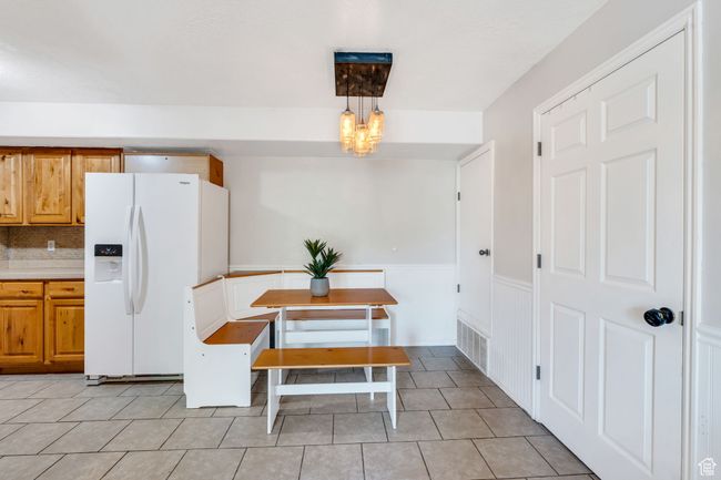 Dining room with a chandelier, a wainscoted wall, and light tile patterned floors | Image 7