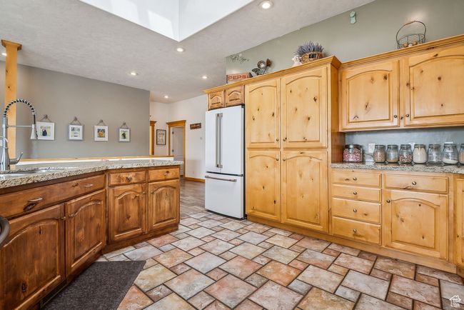 Kitchen with a sink, freestanding refrigerator, recessed lighting, stone finish flooring, and light countertops | Image 14