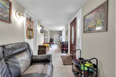 Stepping through the main entry, you are greeted bt the front sunroom. This inviting space sets the tone for a home filled with warmth and charm. At the far end of the sunroom, a door leads to the garage. | Image 2