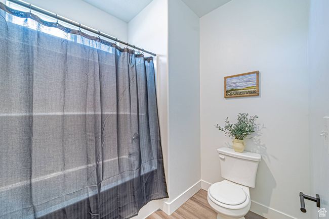 Bathroom featuring toilet, a shower with curtain, wood finished floors, and baseboards | Image 10
