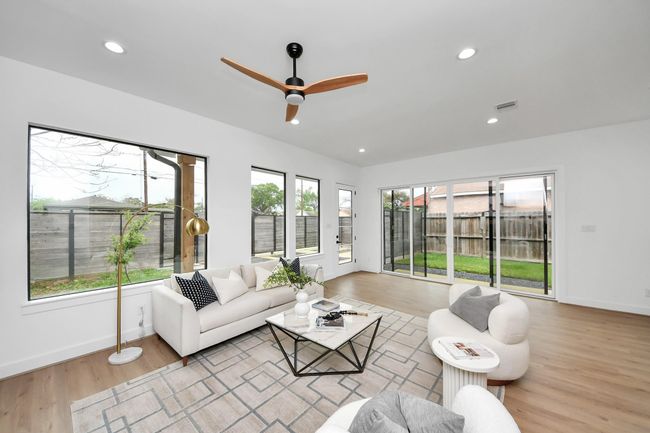 The living room has large windows, ceiling fan, recessed lighting, and sliding glass doors leading to the backyard. | Image 6