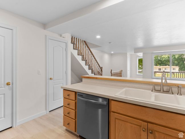Kitchen with stainless steel dishwasher, light wood finished floors, light countertops, and recessed lighting | Image 6
