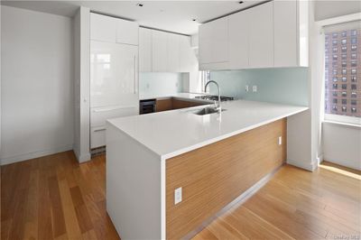 Kitchen with white cabinets, wine cooler, kitchen peninsula, and light hardwood / wood-style flooring | Image 2