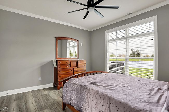 bedroom with wood finished floors, visible vents, a ceiling fan, ornamental molding, and baseboards | Image 33