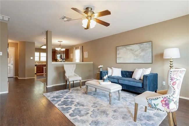 Living area featuring a ceiling fan, dark wood-type flooring, a chandelier, and baseboards | Image 4