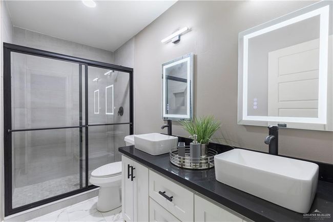 Full bath featuring marble finish flooring, toilet, a shower stall, and double vanity | Image 8