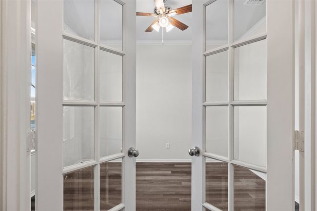 Spacious office featuring laminate/ wood-style floors, ceiling fan, and french doors | Image 12