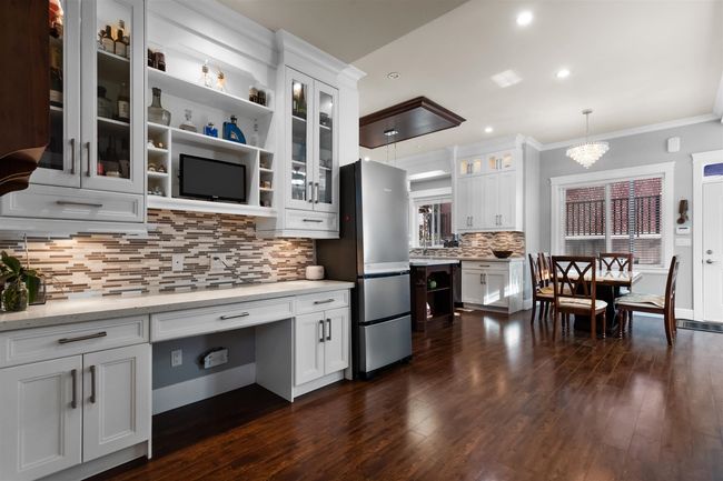 Kitchen with freestanding refrigerator, crown molding, dark wood-style floors, white cabinets, and recessed lighting | Image 10