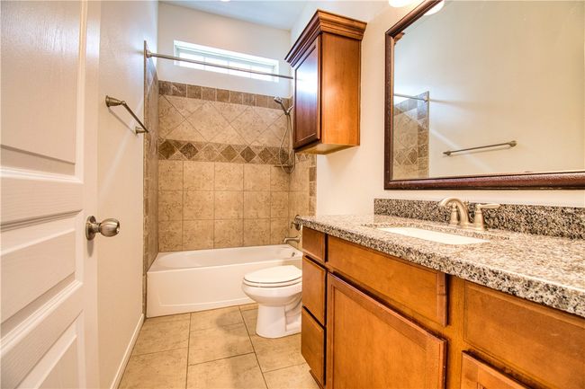 Bathroom with toilet, vanity, tile patterned floors, and bathtub / shower combination | Image 5