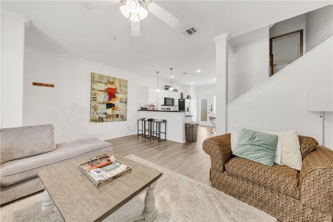 Living area with crown molding, visible vents, a ceiling fan, and light wood finished floors | Image 4