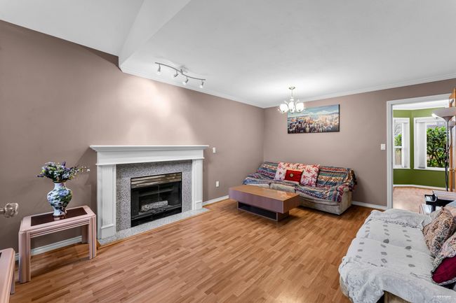 Living room with crown molding, wood finished floors, an inviting chandelier, and baseboards | Image 6
