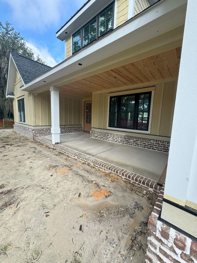 Doorway to property featuring brick siding, a porch, and roof with shingles | Image 13